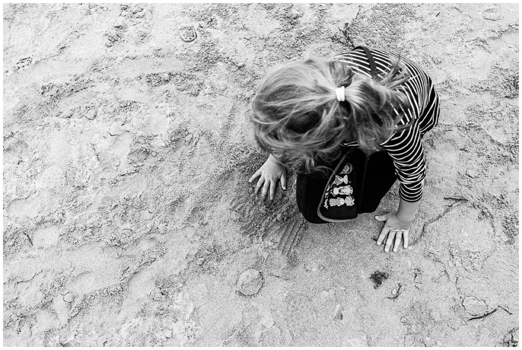 petite fille qui touche le sable