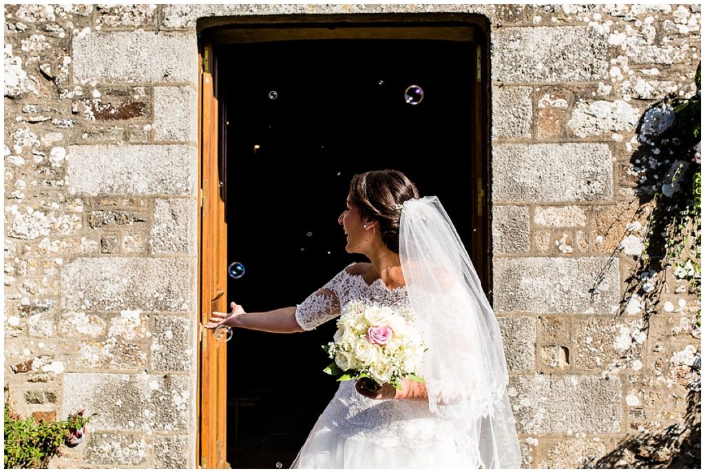 mariée qui joue avec les bulles à la sortie de l'église